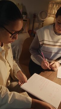 Vertical shot of young math tutor watching student doing test and checking her answers during lesson