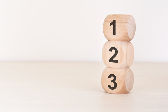 123 wooden blocks stacked vertically on a light desk. Numbers 1, 2, 3 concept for steps, priority, beginning, or simple education. Copy space.