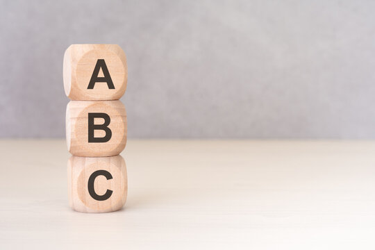 ABC wooden blocks stacked vertically on a light desk. Concept of basics, beginning, alphabet, elementary education or simple steps. Copy space.
