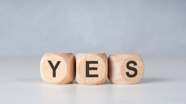 YES word on wooden blocks on a minimalist light grey background. Concept of agreement, positive answer, success, choice and confident decision making. Copy space.