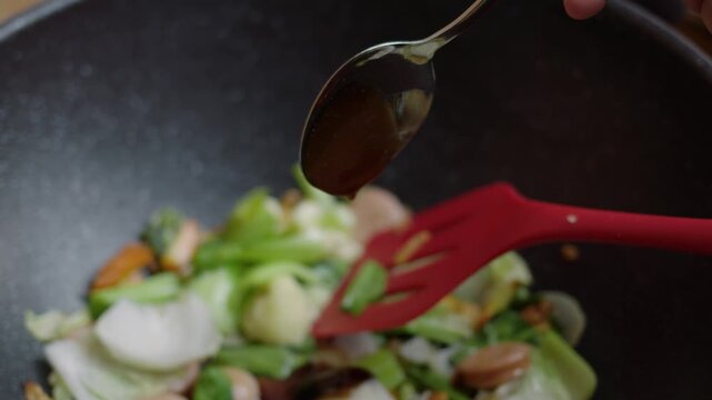 close-up view of Hand pour oyster sauce into the dish. Capcay or chop suey (Chinese food) cooking process. Close Up view and selective focus