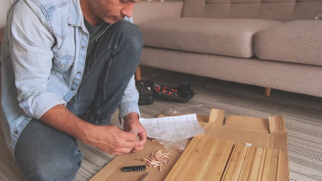 Man organizing hardware parts for furniture assembly on the floor