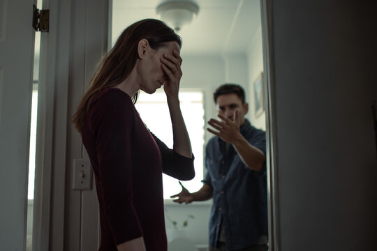 woman covering face during argument with partner at home, relationship conflict and emotional distress concept
