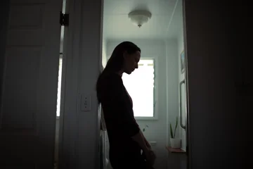 Selbstklebende Fototapeten Altes Krankenhaus Beelitz silhouette of tired woman leaning against wall in bathroom, stress and mental health concept   © kieferpix