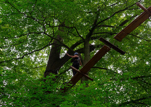 Active girl balancing on wooden beam in high ropes course