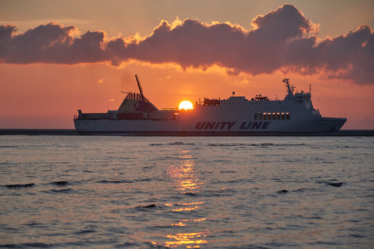 SWINOUJSCIE, WEST POMERANIAN VOIVODESHIP, POLAND - June 26, 2021: Unity Line Ferry Ship Sailing past Stawa Mlyny Windmill Lighthouse at Sunrise in Swinoujscie Port