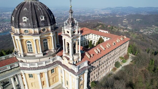 Aerial drone view of the majestic Basilica of Superga and its monastery buildings on the hilltop in Turin, Italy, historic baroque architecture, city panorama, sunny daylight.