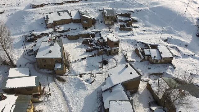 Aerial view of snowy traditional poor village houses across rural Pakistan in winter. Cold season geography reveals village life and housing patterns seen clearly from above.