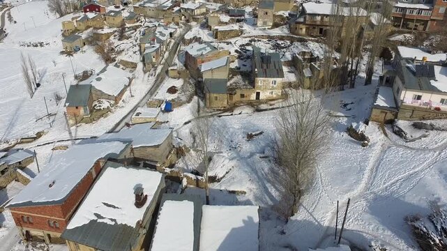 Aerial view of snowy traditional poor village houses across rural Pakistan in winter. Cold season geography reveals village life and housing patterns seen clearly from above.