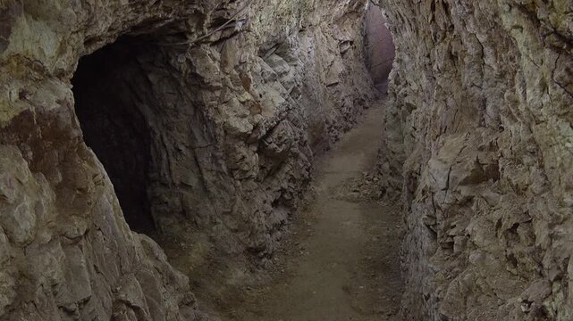 Mysterious dark cave interior revealing ancient rocky walls and shadowy underground chamber passage. Dramatic creepy cavern hall with textured stone formations creating eerie atmospheric environment.