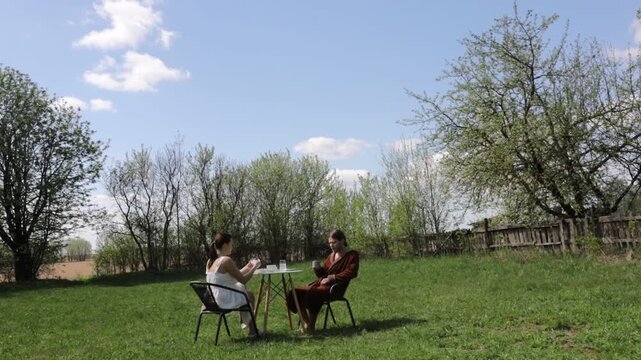 A loving couple is having breakfast at a table in the garden in spring