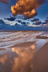 Fototapeta premium Dramatic Sunset Sky Reflected on Wet Beach Sand with Ocean Waves and Groynes