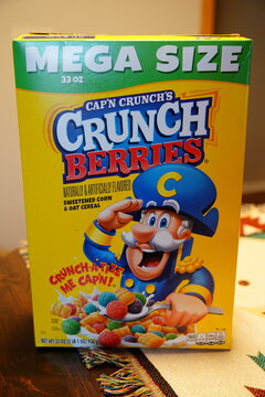 ​A box of Cap'n Crunch's Crunch Berries cereal, featuring the iconic captain character mascot on a bright yellow background.
