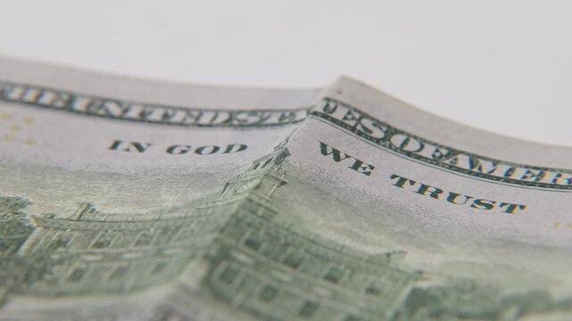 Printed text of In God We Trust on paper money dollar bill of high value and American economy from United States printed cash bills on close up surface of print texture and USA government building