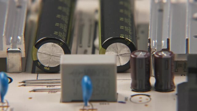 Close up slow motion of TV television video power supply electronic electronics board for internal media with transisteos, transformers, heat sink, and small wires and cables attached to inside device
