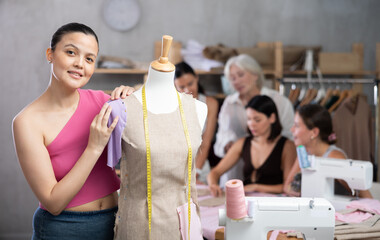 Young woman working with mannequin during sewing master class in workshop