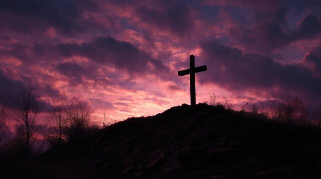 Silhouette of a Christian cross on a hill at sunset. Dramatic purple sky with clouds for Good Friday and Easter. Religious background with copy space