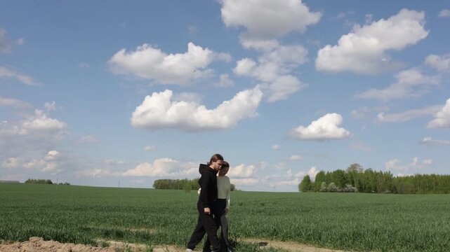a loving couple walking through a field in summer