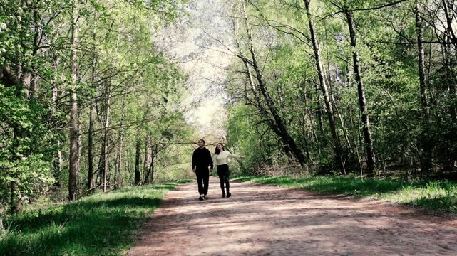 a young couple walking along a road in a spring forest