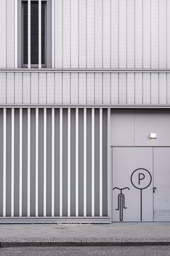 Urban concrete wall facade shows minimal vertical stripes and subtle sign detail for contemporary architecture background with orderly lines