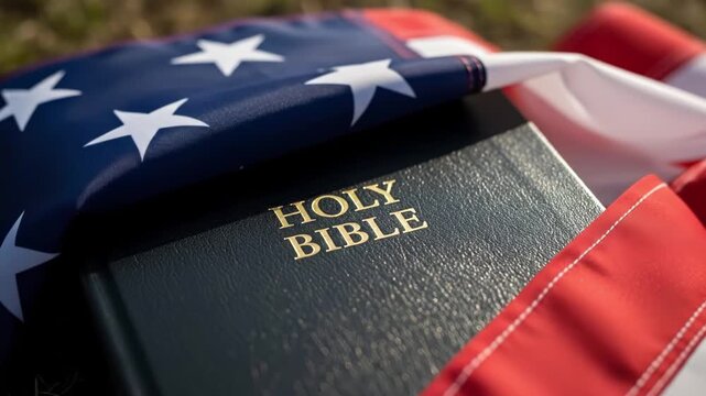 Close-up of a Holy Bible draped with the American flag in natural outdoor light. Concept of religious freedom, christianity and american patriotism