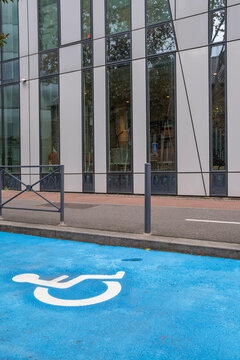 Urban blue accessibility symbol beneath glass reflections on minimal architecture facade delivers clean detail for contemporary building background design