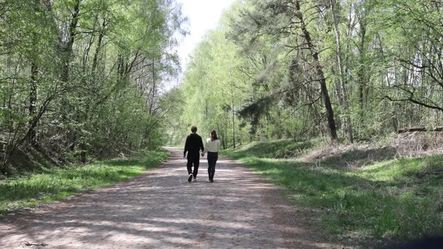 a young couple walking along a road in a spring forest
