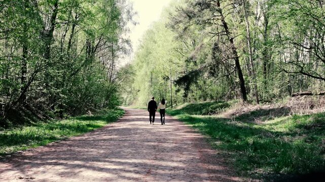 a young couple walking along a road in a spring forest