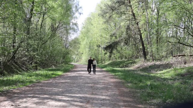 a young couple walking along a road in a spring forest