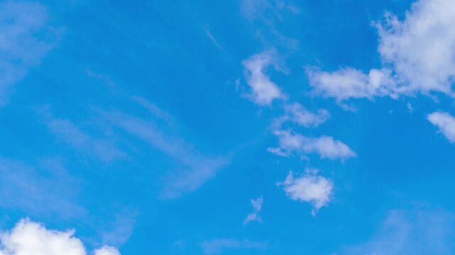 Timelapse of fluffy white cumulus clouds drift across bright blue sky and changing shape on sunny day. Peaceful and airy atmosphere. 4K time lapse footage.