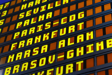 Airport flight information board showing destination cities for travelers