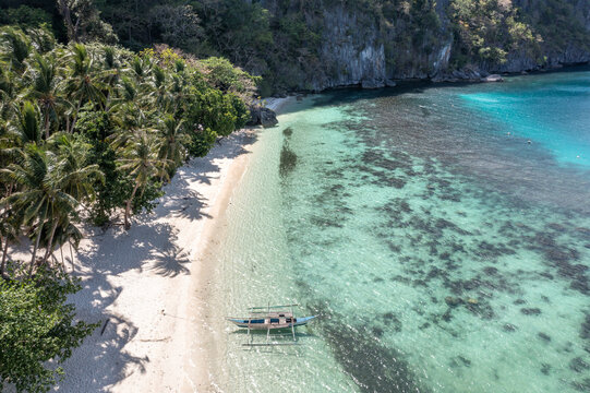 Aerial top-down view of Seven Commandos Beach with turquoise water, white sand and palm trees