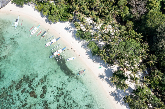 Drone top-down view of boats anchored at Seven Commandos Beach with crystal clear turquoise water