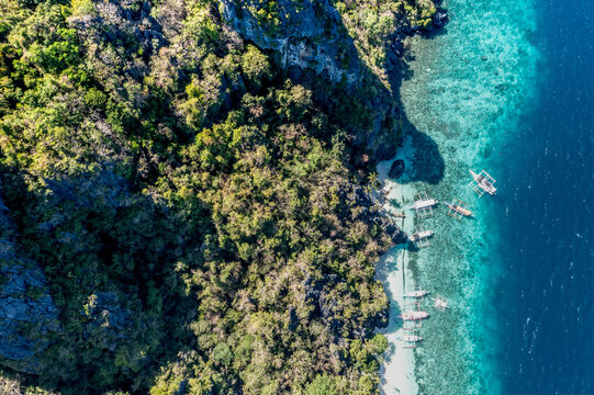 Top down aerial traditional boats on turquoise water Seven Commandos Beach El Nido