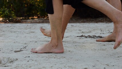 Male and female legs of pair walking on sandy beach. Bare feet of couple stepping along sand shore at sunny day. Lovers spending time together at resort. Concept of summer vacation or holiday