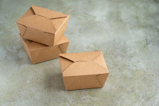 Food takeout box, 100% recycled brown paperboard container on a green background, eco friendly disposable packaging for to-go meal pickup and delivery
