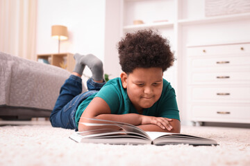 Boy reading book on floor at home