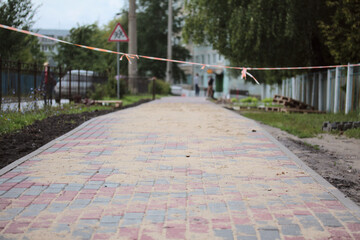 New paving slabs and barrier tape on a pedestrian walkway under repair