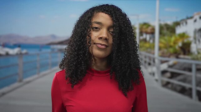 African american woman wearing red top and leather watch with eyes closed presses hands together on street; serenity.