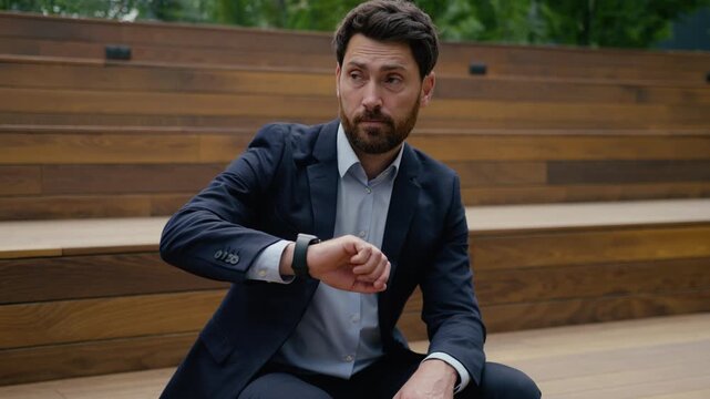 Upset Caucasian business man wait on stairs outdoor late meeting date check time nervous anxious middle-aged guy businessman impatient sad male in city hand wristwatch clock waiting deadline lateness
