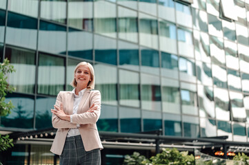 Fototapeta premium Smiling businesswoman standing confident in corporate building exterior