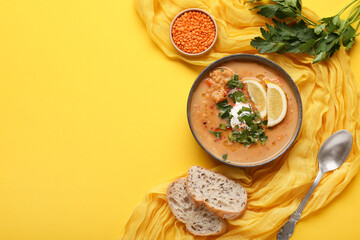 Creamy red lentil soup with lemon slices, parsley and yogurt in bowl, served with bread on yellow background, top view with copy space © Pixel-Shot