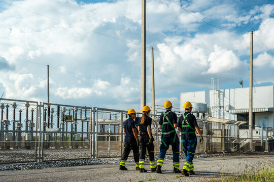 Electrical engineering team conducting walkdown at high-voltage substation facility. Specialists inspecting power grid transmission infrastructure and utility network.