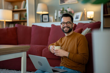 Fototapeta premium Young man smiling working from home with laptop