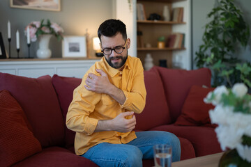 Obraz premium Man feeling shoulder pain and discomfort at home