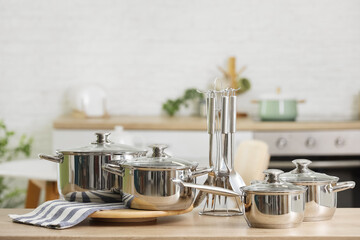Stainless cooking pots and utensils on table in kitchen