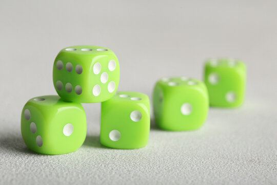 Green game dices on light background, closeup
