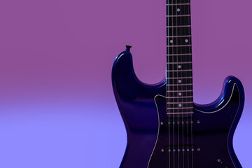 Modern electric guitar on purple background, closeup