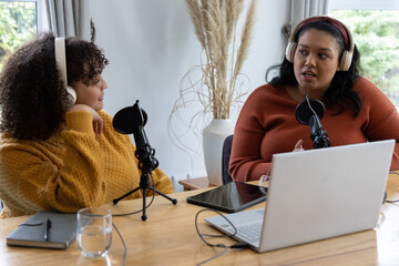 African American women recording podcast in home studio wearing mustard and rust sweaters with mics