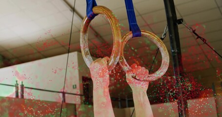 Gripping athlete's hands pulling on wood gymnastic rings at gym, with blue straps rigging and chalk